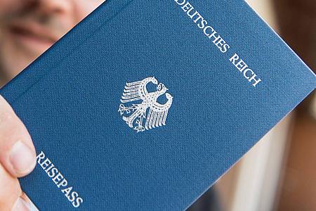 Ein Mann hält ein Heft mit dem Aufdruck «Deutsches Reich Reisepass» in der Hand. Sogenannte Reichsbürger leugnen die Existenz der Bundesrepublik Deutschland.