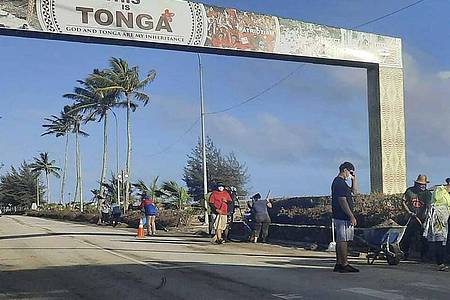 Aufräumarbeiten auf einer Straße in Nuku`alofa. Sechs Tage nach der Eruption eines Untersee-Vulkans vor Tonga ist der Flughafen des Südsee-Archipels wieder funktionsfähig. Foto: Marian Kupu/Broadcom Broadcasting/AP/dpa