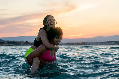 Zwei Frauen stehen lachend im Meer