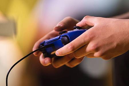 Ein Spieler hält einen Playstation-Controller in den Händen.