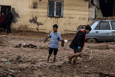 Kinder gehen nach heftigen Regenfällen in der Türkei eine schlammige Straße entlang.