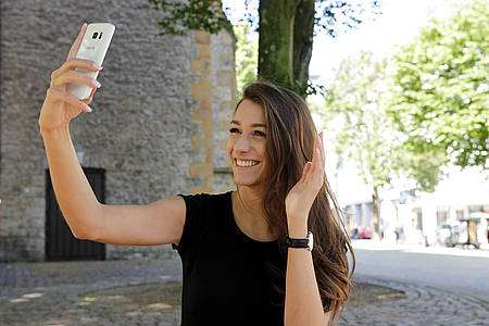 Frau lächelt in Smartphone-Kamera
