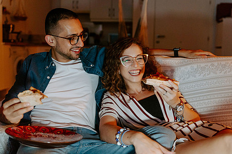 Mann und Frau sitzen auf dem Sofa und schauen Serie